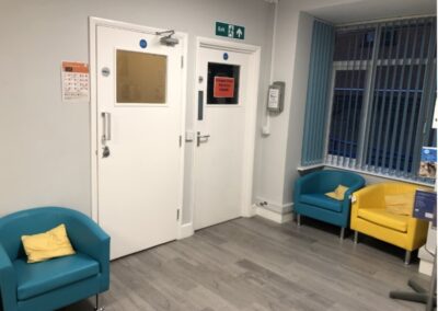 room with 2 blue comfy seats and a yellow seat next to them with two white doors in background