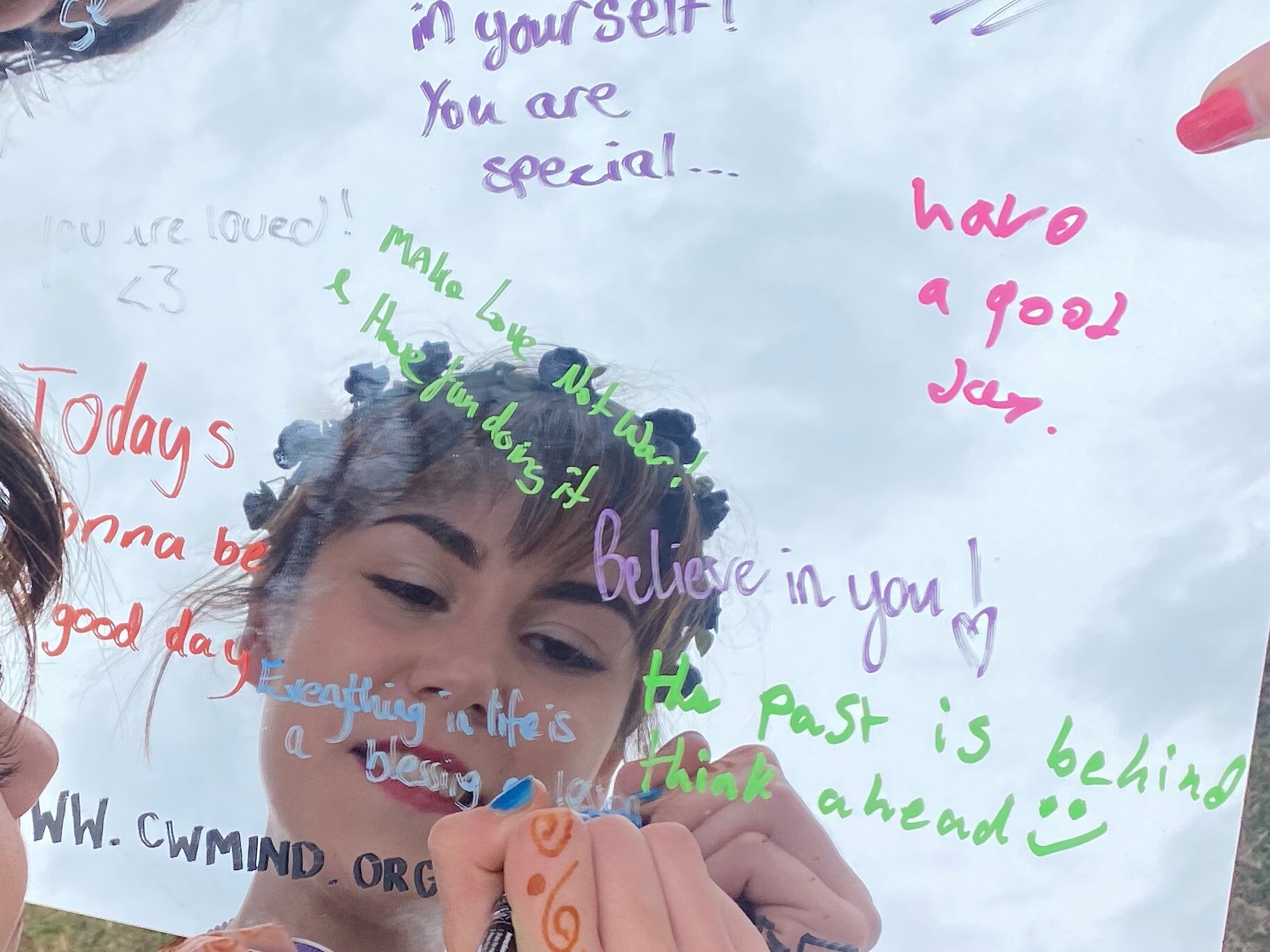 Young girl writing positive affirmations on a mirror