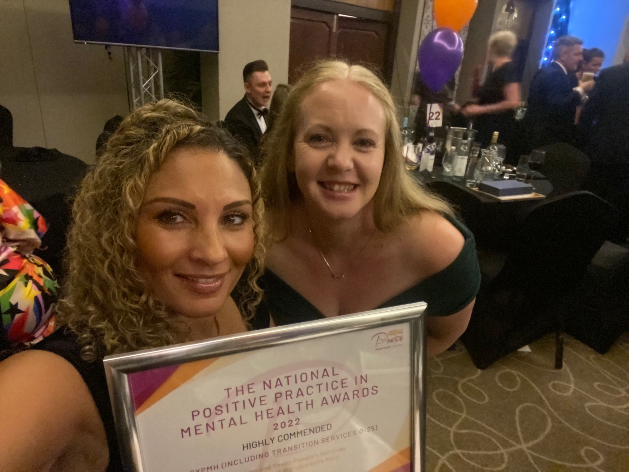 Two women in smart dresses holding a certificate