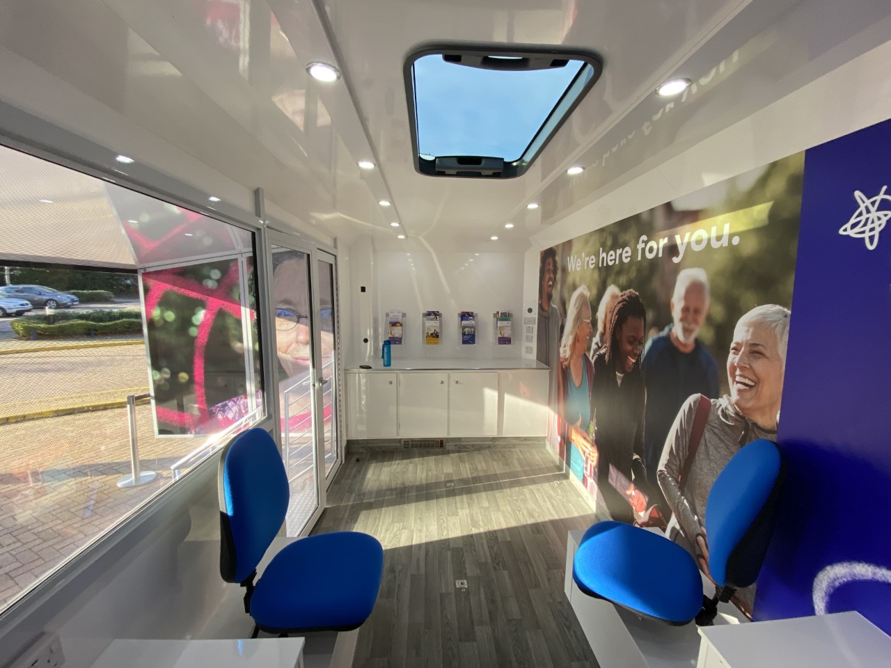 Interior of a vehicle with seats, a wooden floor, skylight and leaflet racks