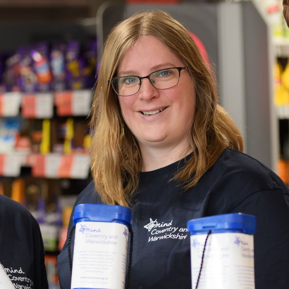 A woman in a Coventry and Warwickshire Mind T-shirt holding collection tins