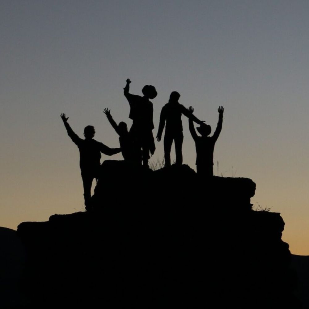 A silhouette of 5 people reaching the summit