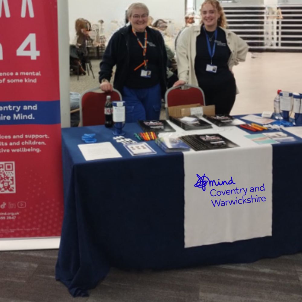 Two staff members behind a Coventry and Warwickshire Mind stall.
