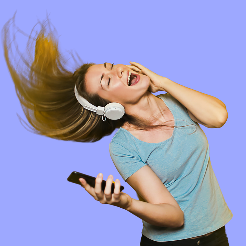 A lady listening to music whilst dancing holding a phone.