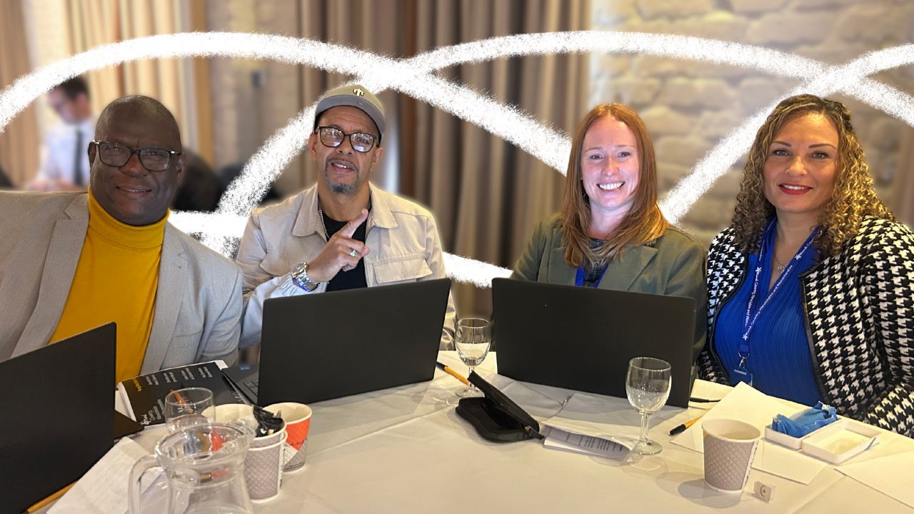 Two men and two women sat around a table with laptops.