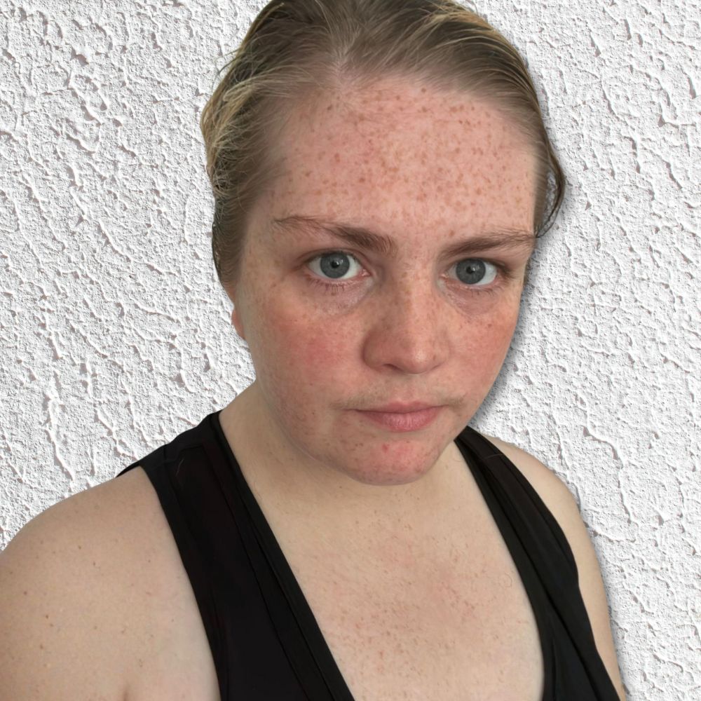 Young woman wearing a black tank top with light hair tied back.